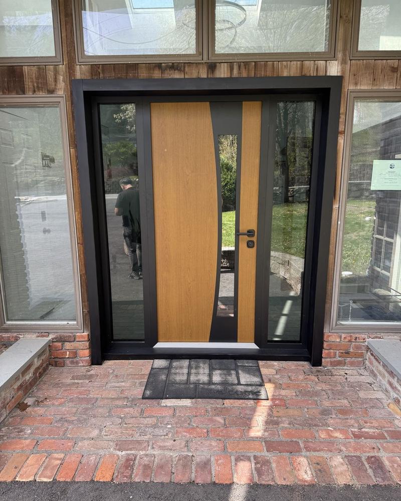 Oversized wood entry door with a curved glass panel and full-height sidelights