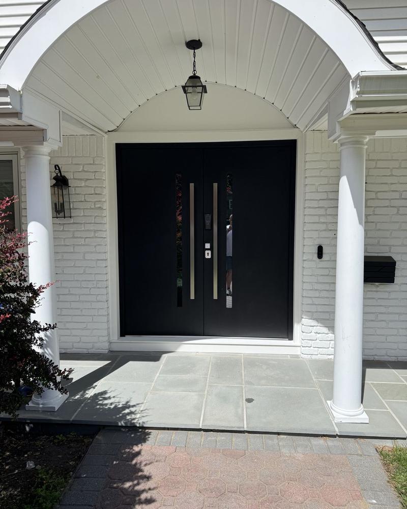 Black double entry door under an arched portico on a white brick house