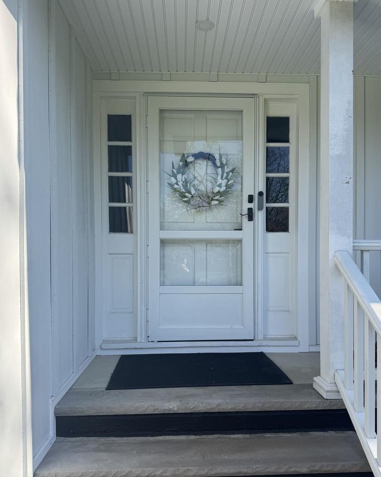 Painted white entry door with glass panels on a brick porch