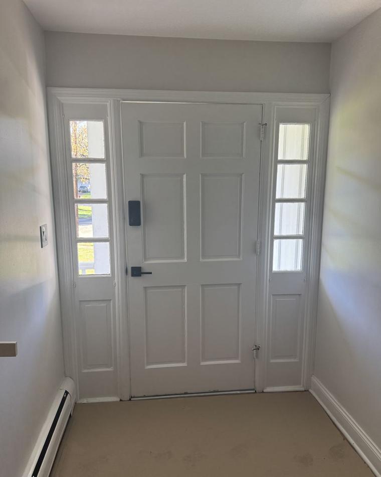 White panel entry door with sidelights, seen from inside the hall